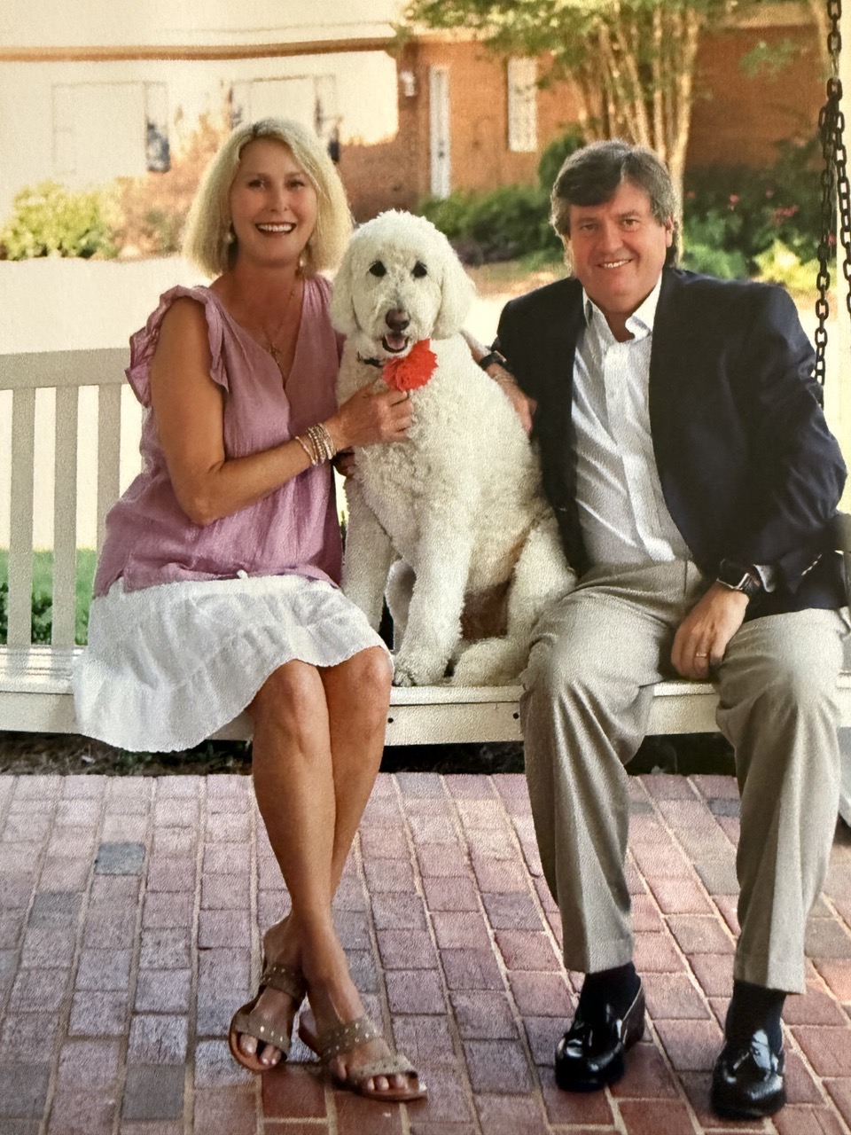 Melissa and her husband Frank on a porch swing with their family dog Muffy